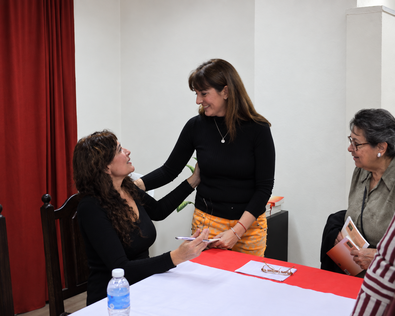 Patricia conversa con una asistente junto a la mesa de firma de ejemplares en Escobar